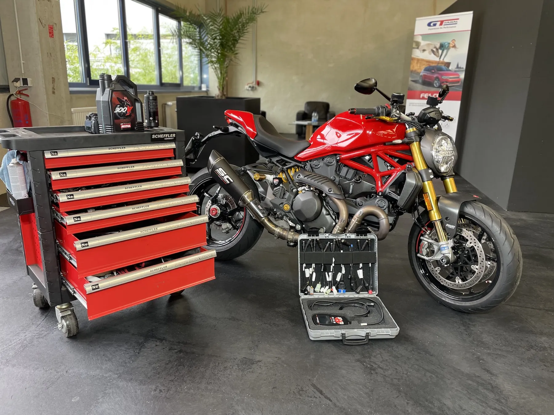 Rote Ducati Monster in der Werkstatt von MKM Börs neben Werkzeugwagen und Diagnosekoffer